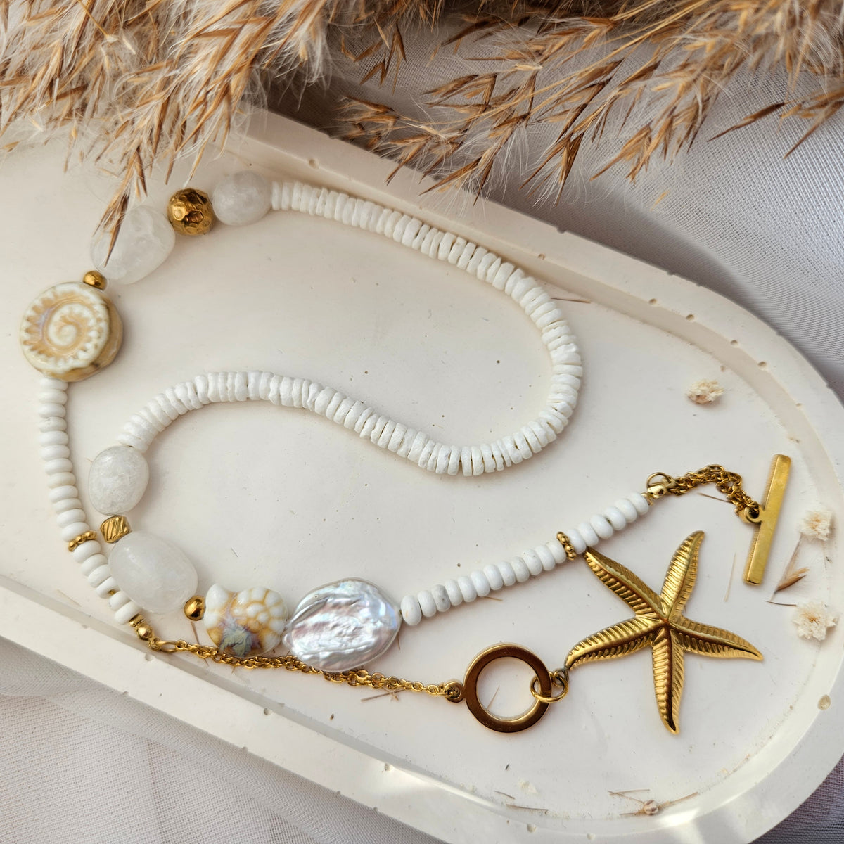 White beaded necklace with a starfish pendant, white howlite, shell beads, white jade and silver-tone stainless steel details.