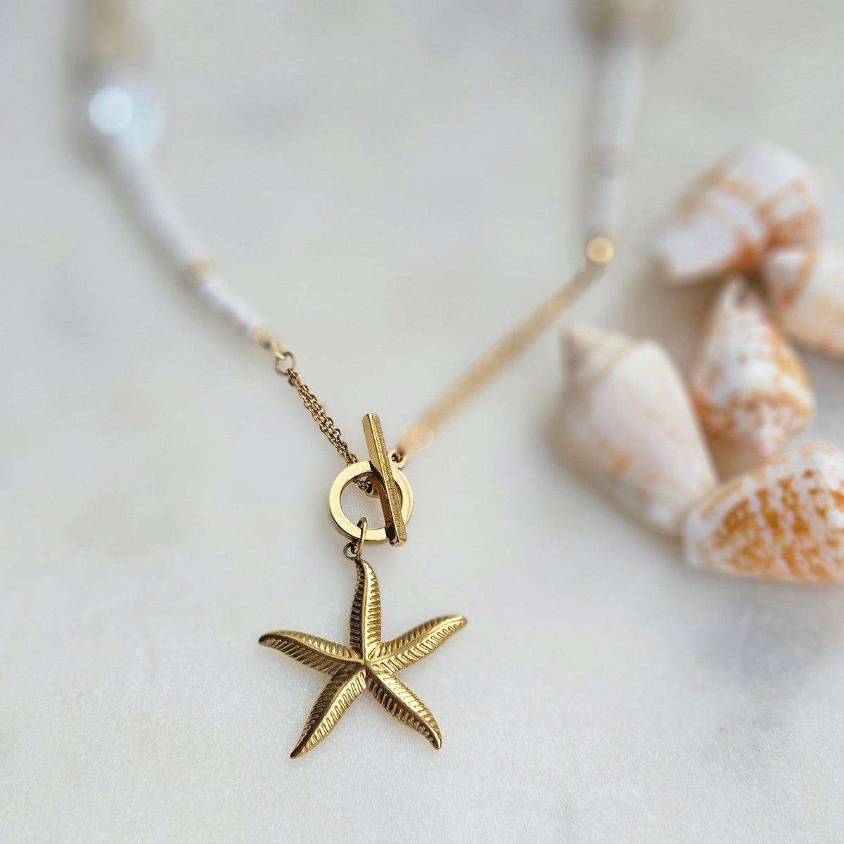 White beaded necklace with a starfish pendant, white howlite, shell beads, white jade and silver-tone stainless steel details.